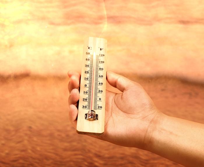 hand holding thermometer in high temperatures  