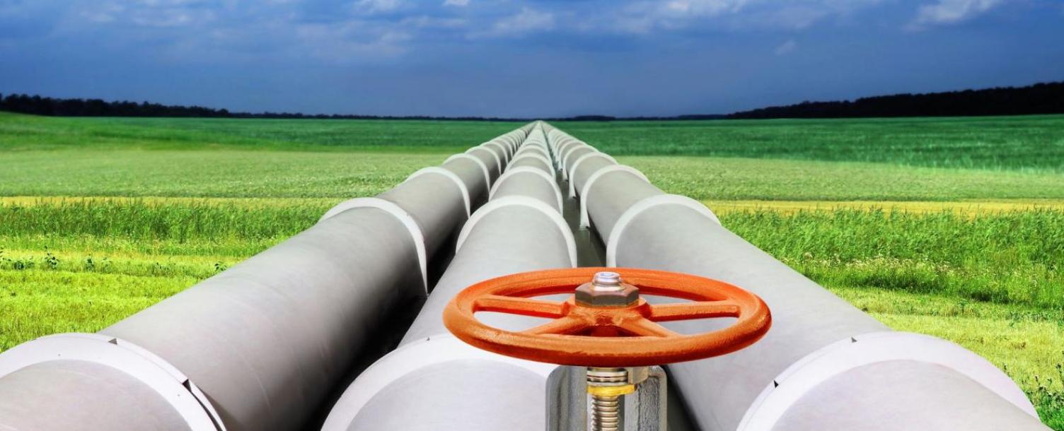 Utility pipes stretching into the horizon between grass and sky